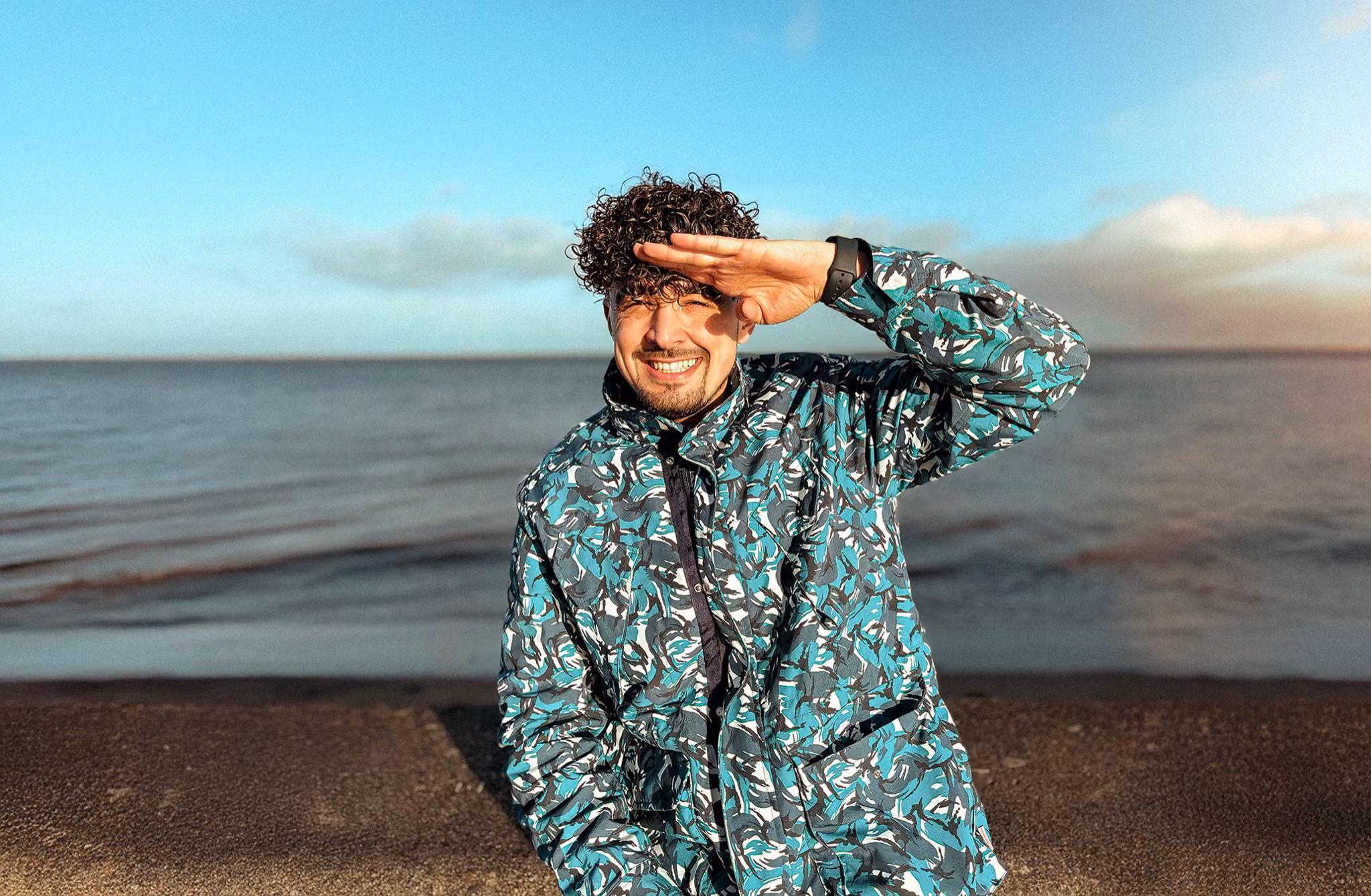 Gorka Di Capitan sonriendo junto al mar en Escocia, protegiéndose los ojos del sol