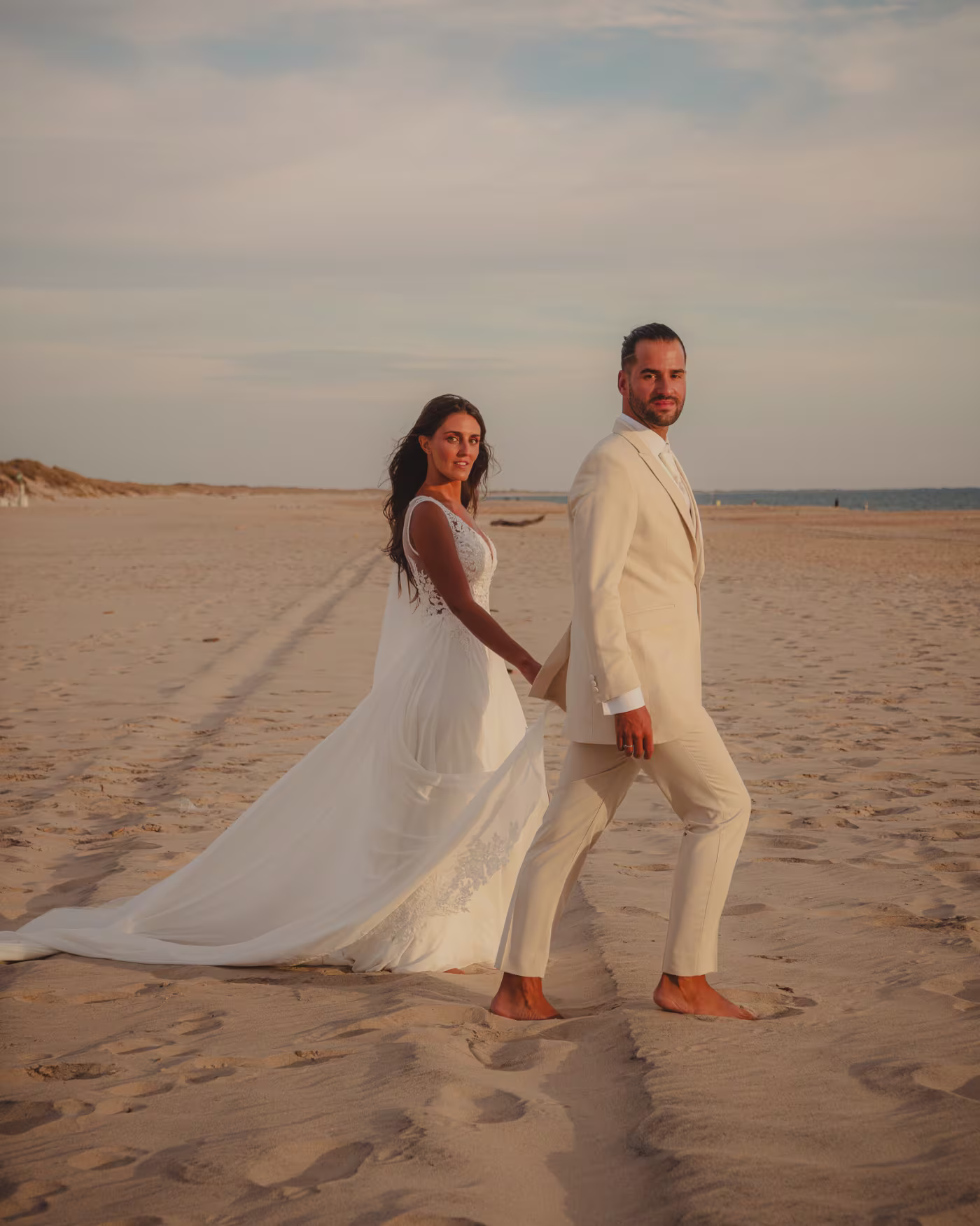 Los novios caminando descalzos por la orilla a la hora dorada en Huelva