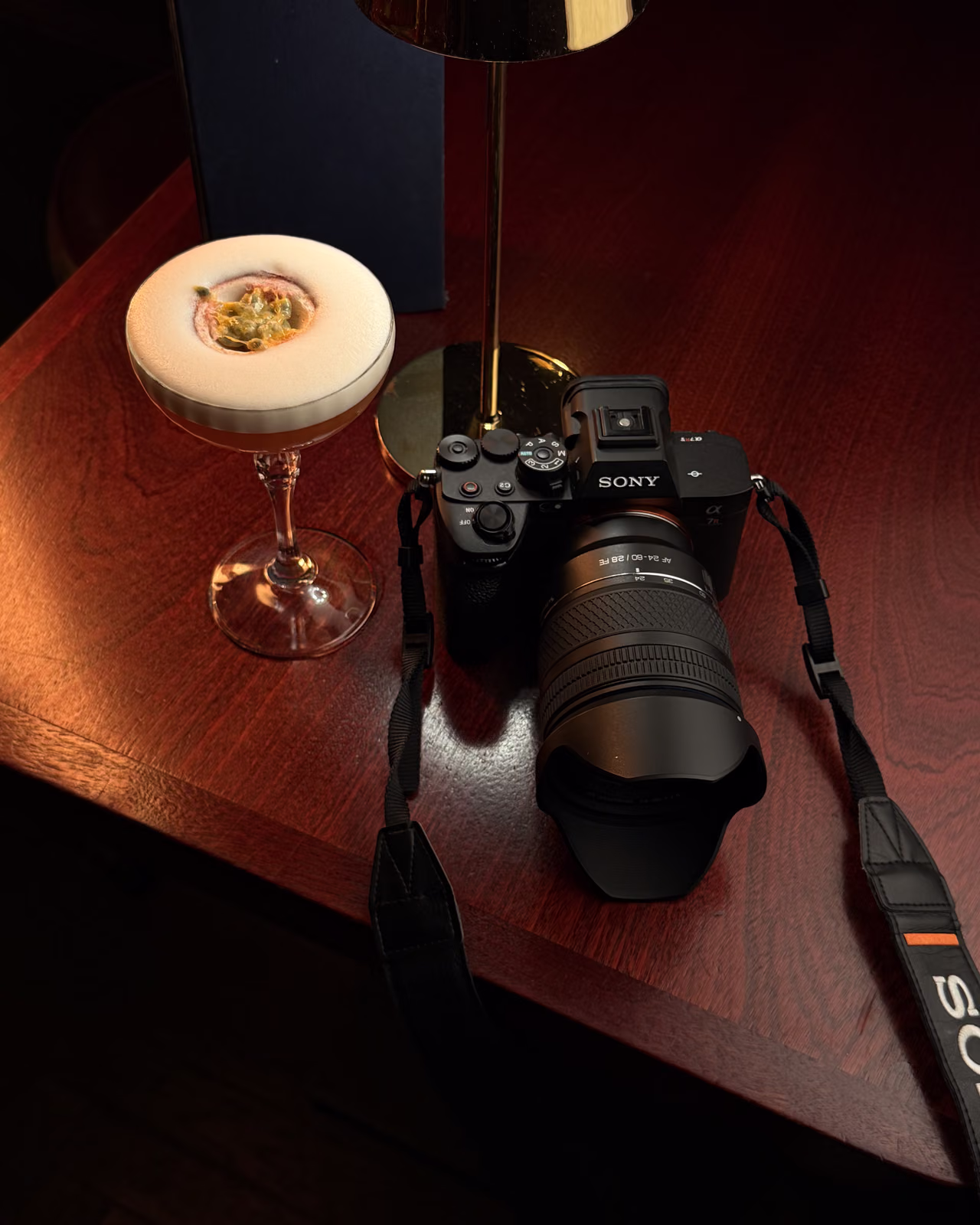 Cámara Sony y un cóctel de fruta de la pasión en la mesa de madera de un bar de Edimburgo durante el Fringe