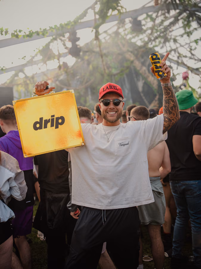 Festival-goer holding up a DRIP branded case and can at Terminal V