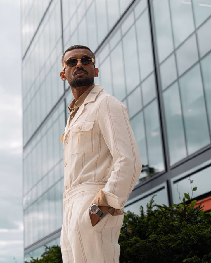 Ehab Ali in a white suit and sunglasses against a glass building, Edinburgh