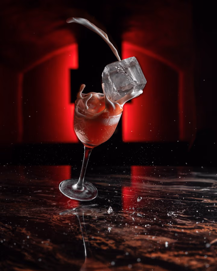 Ice cube crashing into a tilted red cocktail on marble at Encore, Edinburgh
