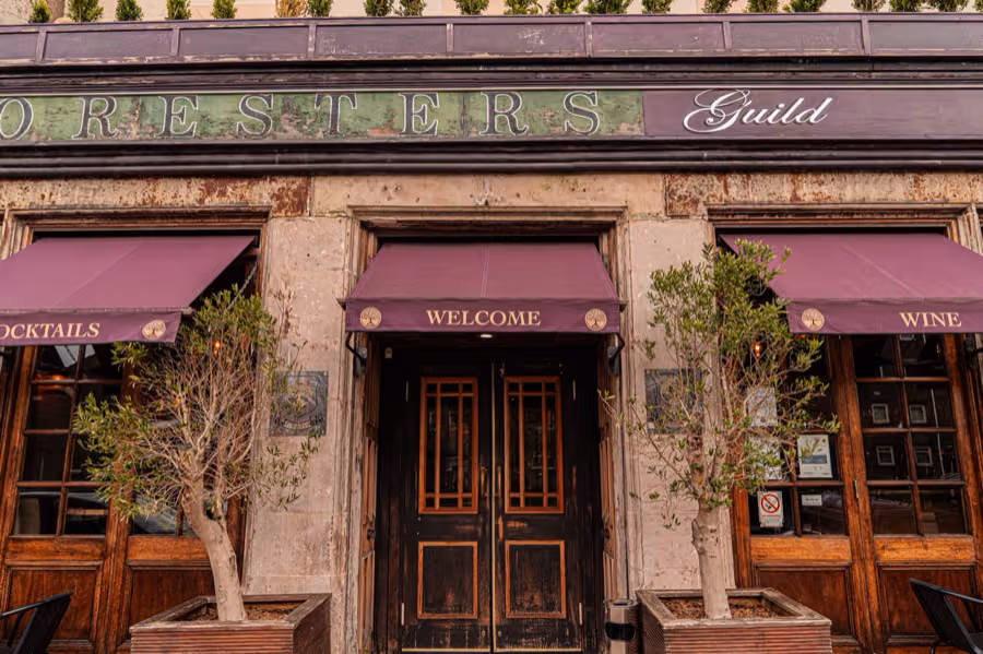 Front entrance of Foresters Guild framed by trees under its purple awnings in Portobello, Edinburgh