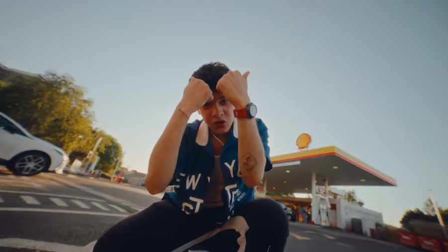 Artist crouching at a petrol station for the Heavy Energy music video