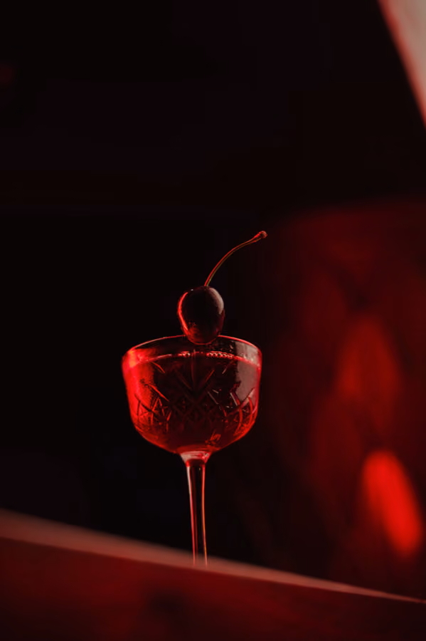 Red coupe with a cocktail cherry glowing against a dark background at Jackson The Tailor, Edinburgh