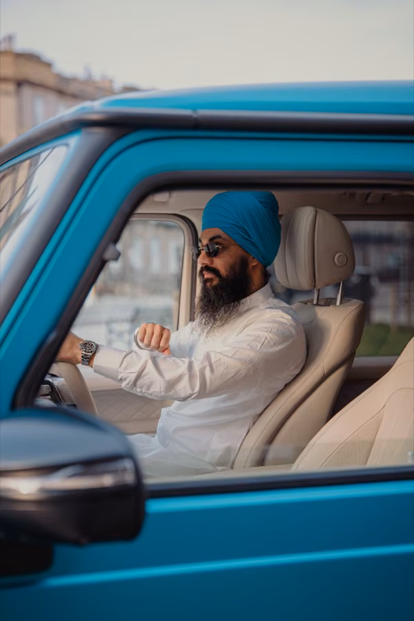 Suraj checking his watch at the wheel of his turquoise Mercedes G-Wagon, Edinburgh