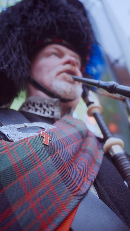 Piper wearing a Tennent's tartan sash and pin at The Second Stadium fan event